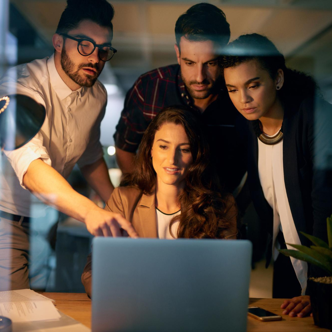 Professional team collaborating around laptop in modern office environment